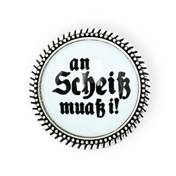 Gaudibroschn „An Scheiß muaß i!“ in Silber, sicher befestigt an einem Dirndl