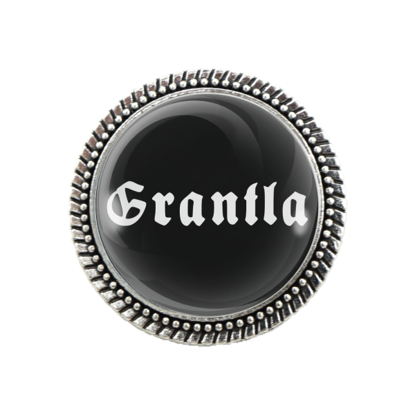 Detailansicht der Brosche „Grantler“ mit schwarzem Grund und weißer Schrift